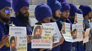 Activists of Sikh Nihangs - religious Sikh warriors - from the Jatha Neeliyan Faujan organization hold placards as they protest against the film 'Nanak Shah Fakir' outside the Golden temple in Amritsar on April 9, 2015.