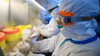 Workers in protective suits conduct RNA tests on specimens in a laboratory in Taiyuan, China