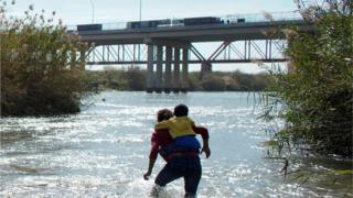 Мигранты из Гондураса идут по реке, пытаясь пересечь Рио-Браво в направлении Соединенных Штатов, как видно из Пьедрас-Неграс, Мексика, 16 февраля 2019 г.