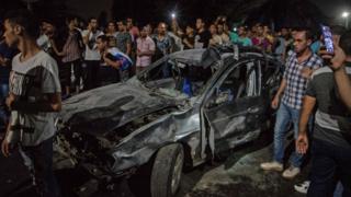السيارة التي انفجرت في محيط معهد الأورام بوسط القاهرة ويحيط بها حشد من الناس الذين روعهم الحادث.