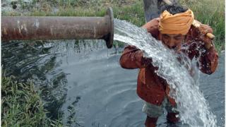 ஆழ்துளை கிணற்றிலிருந்து வரும் தண்ணீரை குடிக்கும் விவசாயி
