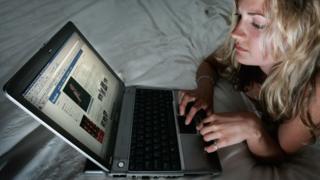 فتاة تجلس أمام الكمبيوتر المحمول