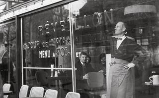 Ein Kellner malt ein Schild in ein Restaurantfenster