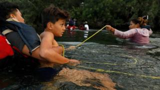 Una familia se sujeta a una soga para cruzar el río