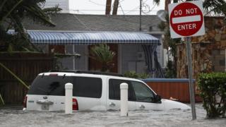 Una camioneta en mitad de una calle inundada.