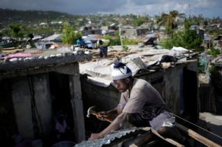 A man fixes the roof of a house affected by Hurricane Matthew in Jeremie, Haiti