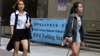 两名年轻女士在香港中环一处投票站外走过(BBC中文网图片11/12/2016)