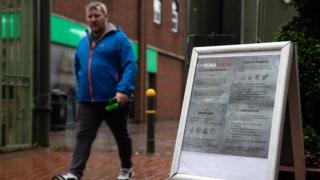 man walking past sign