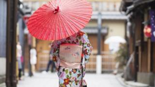 Japanese woman walking with traditional umbrella in Kyoto