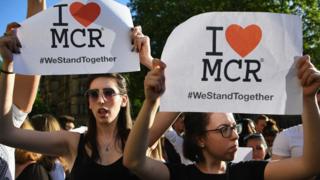 People at Manchester vigil holding signs