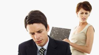 A woman looking over the shoulder of a man working