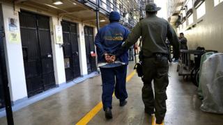 Un oficial armado del Departamento de Corrección y Rehabilitación de California (CDCR) escolta a un recluso condenado el 15 de agosto de 2016, condenado a muerte en la Prisión Estatal de San Quentin en San Quentin, California