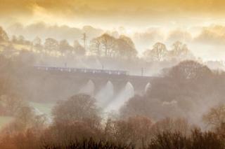 in_pictures Mist is seen in countryside scene as a train crosses a viaduct
