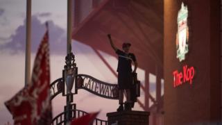 Boy standing on gates outside Anfield