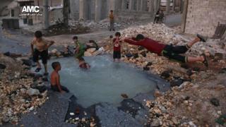 Un cráter sirve de estanque para los niños en Alepo