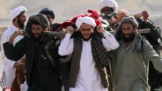 People carry the dead body of a child to be buried after he was killed on the edge of Herat city, Afghanistan 25 August 2015
