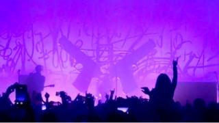 Grab from a video shows guns on stage just before falling