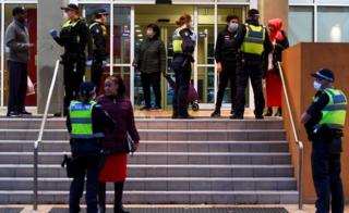 Polizisten sprechen mit Bewohnern vor dem Eingang zu einem der Hochhäuser