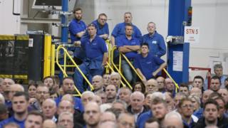 Workers look on as Scottish First Minister Nicola Sturgeon makes a keynote speech