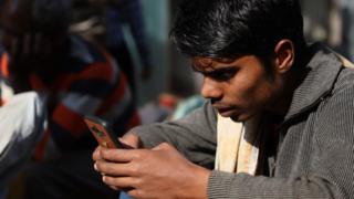 Работник пользуется мобильным телефоном возле станции метро в Старом Дели, Индия, 9 февраля 2019 года.