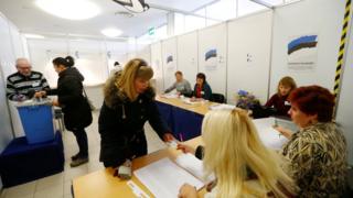 An election official inspects a woman's document during the general election at the polling station in Parnu.