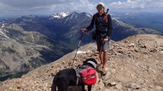 Trevor and Tenille at the top of a mountain with other, snow-capped mountains in the background
