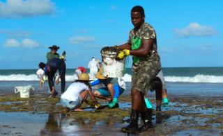 A man works to remove an oil spill on Muro Alto beach in Tamandare, Pernambuco