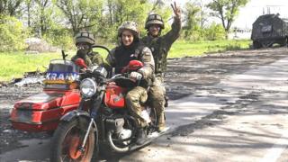 Ukrainian servicemen ride a motorcycle on the road which connects Kharkiv and a village recently retook by the Ukrainian Army