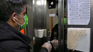 An Iranian man uses small sticks to push the elevator button at an office building in Tehran on March 4, 2020