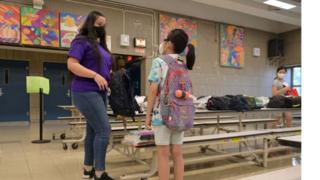 Teacher at an elementary school hands a graduation gift to a pupil at the end of the school year