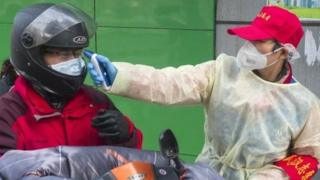 武汉市社区工作人员为进小区者量体温