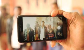 A worker takes a group photo at lost and found camp