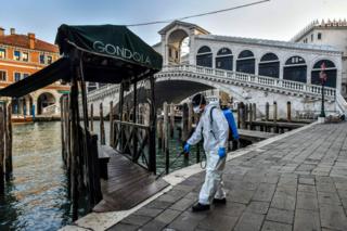 A municipal company employee sprays disinfectant in public areas at the Rialto Bridge in Venice. 11 March 2020.