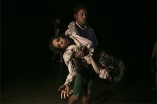 Nobi Hossain carga a Sona Banu hacia la orilla del río Naf. Como ellos, medio millón de rohingyas ha huído a causa de la violencia militar del ejército de Myanmar.