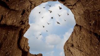 Forma de cabeza en rocas con vista al cielo y pájaros