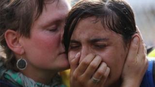 A migrant girl is comforted after being overcome by tear gas, 16 Sept