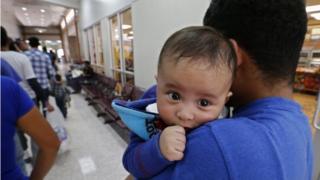 A migrant with an infant waiting in line