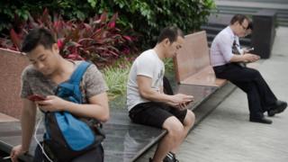 Мужчины на скамейке смотрят на телефоны