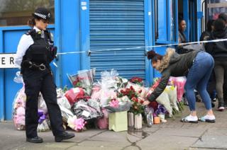 A woman lays flowers on Chalgrove Road, Tottenham, north London.