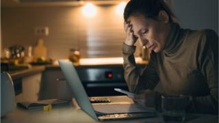 Woman looking at computer and phone