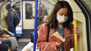 A woman wearing a mask on the London Underground
