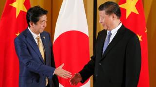 Japanese Prime Minister Shinzo Abe (R) shakes hands with Chinese President Xi Jinping