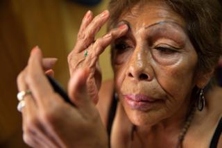 Luchita, a resident of Casa Xochiquetzal, puts on make-up in her bedroom at the shelter