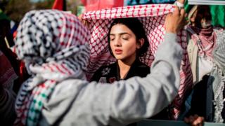 A girl ties the Palestinian Kiffeyyah during a demonstration of members of pro-Palestinian groups and other civil society groups outside the US Consulate General in Sandton district of Johannesburg, on May 15, 2018, to protest against the killing, the day before, of 59 Palestinians in clashes and protests