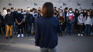 Pupils wearing protective masks stand as they listen to a woman at Françoise-Giroud middle school in Vincennes, east of Paris, on 1 September 2020,