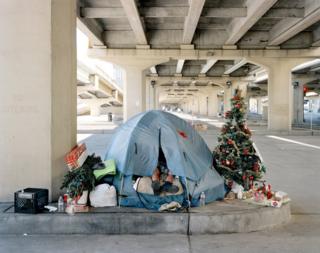 Homeless man in a tent with a Christmas tree