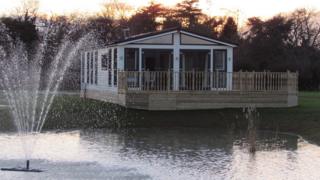 A lodge with a balcony overhanging a lake