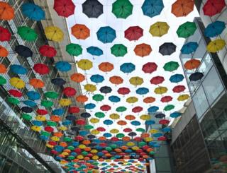 Colourful umbrella's hanging between buildings