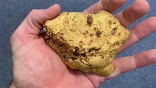 A man holds the gold nugget in his hand