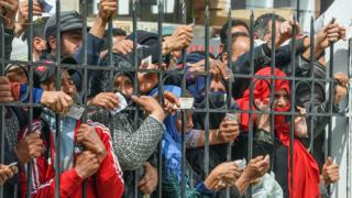 People holding their ID cards outside a government building in Mnihla, Tunisia - Monday 30 March 2020